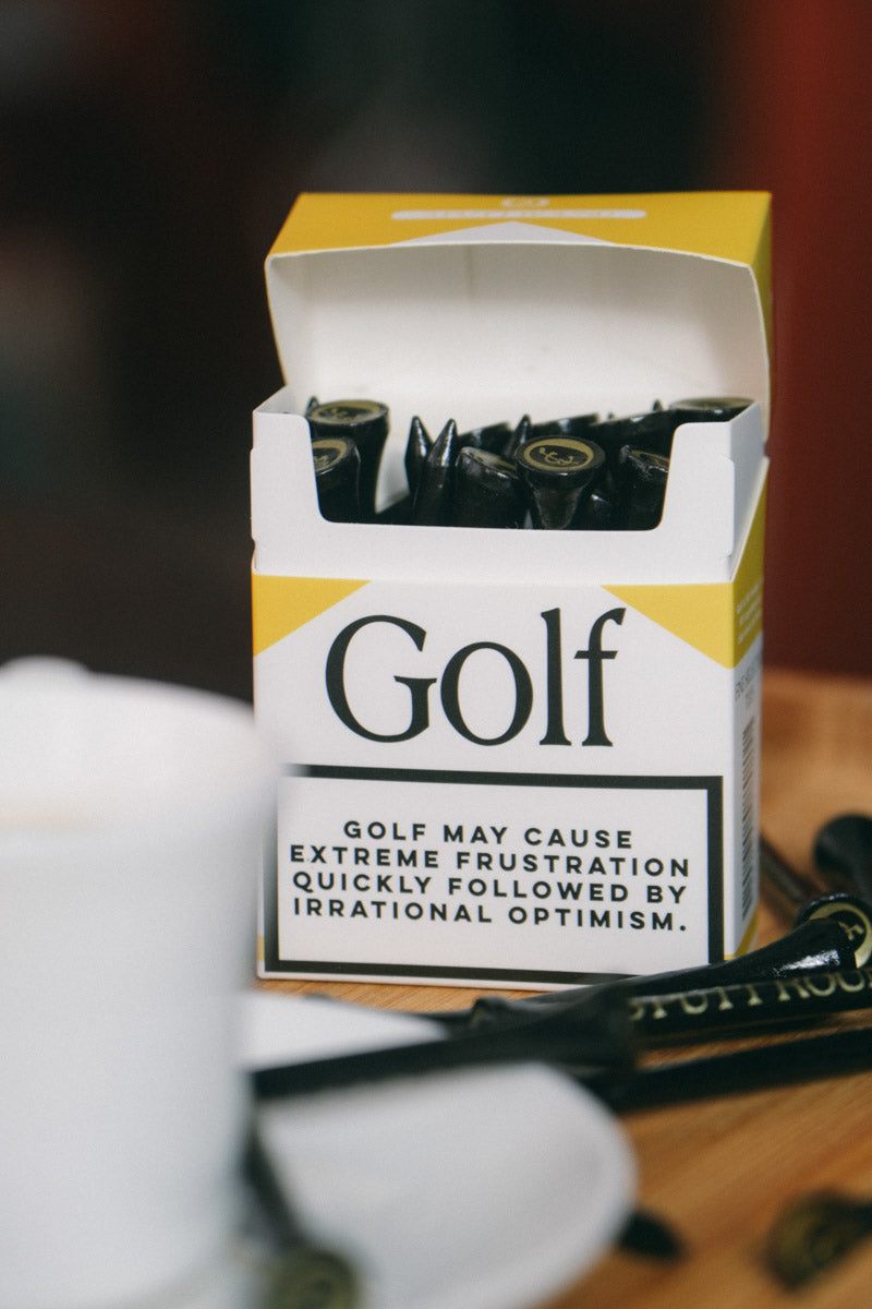Set of three gold golf tees from Three Putt Round's Golf Addiction Tee Pack, featuring branded wooden tees for golf enthusiasts.