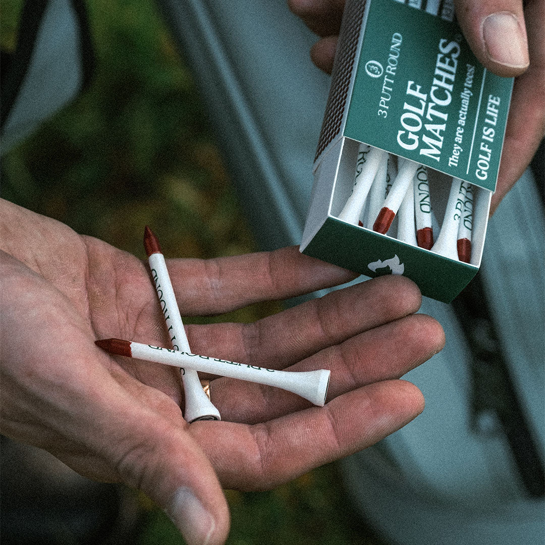 Green golf tee match box by Three Putt Round showing a wooden golf tee inside a compact, green-colored matchbox.